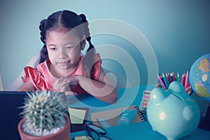 Homeschool kids education internet online by using a computer to study at home. Student Asian little young girl studying looking