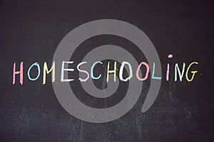 Homeschooling. Child pointing at word Homeschooling on a blackboard photo