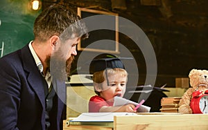 Homeschooling concept. Enthusiastic kid studying with teacher. Father checking homework, helps to boy, son. Teacher in