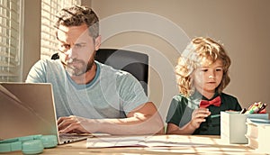 homeschooling and elearning. back to school. serious father and son use computer at home.