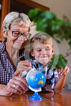 Homeschooling grandmother teaching smart boy, child in geography