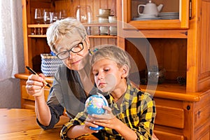 Homeschooling grandmother teaching smart boy, child in geography