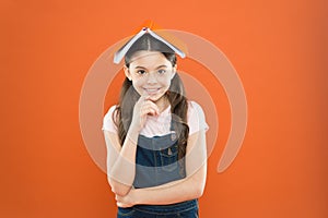 Homeschooling and private lesson. Book on her head. Little girl book roof head. Small girl book orange background