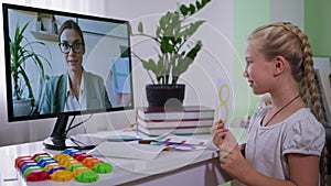 Homeschooling, smiling girl during online education listens to teacher by remote meeting due to coronavirus pandemic via