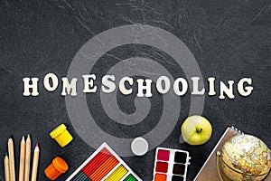 Homeschooling word made of wooden letters on a black background, top view.