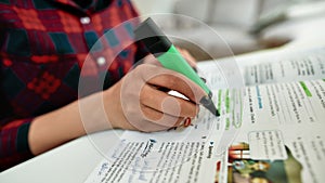 Homework. Cropped shot of a female student learning English, studying at home. Making some notes in textbook photo