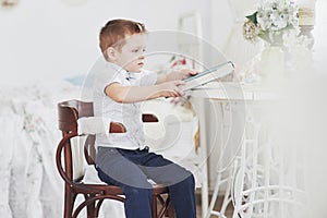 Homework and school concept - bored student boy reading book or textbook at home