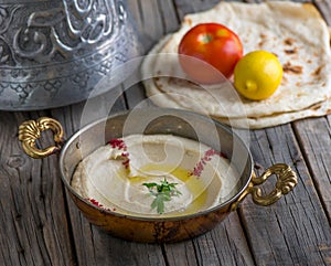 Hommous with pita served in dish side view on wooden table background