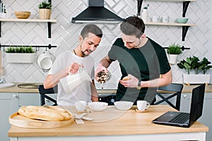 Homosexual couple, gay people, same sex marriage between Caucasian men. Male partners having breakfast and cooking in