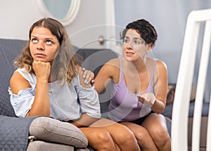 Homosexual couple of two lesbian women at home on sofa quarreled, one asks for forgiveness, crying after arguing