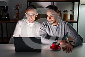 Homosexual couple using computer laptop with a happy and cool smile on face