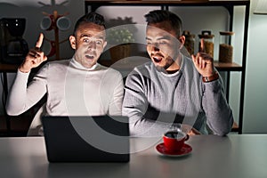 Homosexual couple using computer laptop pointing finger up with successful idea