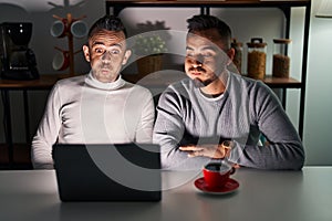 Homosexual couple using computer laptop puffing cheeks with funny face
