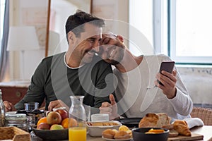 Homosexual men sitting at kitchen table and laughing