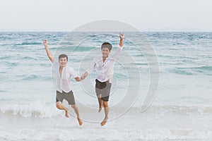 Homosexual portrait young asian couple running and jump with cheerful together on beach in summer