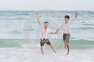 Homosexual portrait young asian couple running and jump with cheerful together on beach in summer