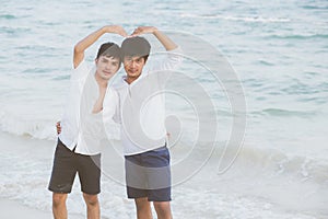 Homosexual portrait young asian couple stand gesture heart shape together on beach in summer