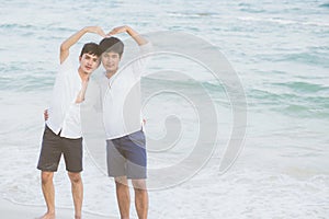Homosexual portrait young asian couple stand gesture heart shape together on beach in summer