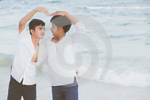 Homosexual portrait young asian couple stand gesture heart shape together on beach in summer