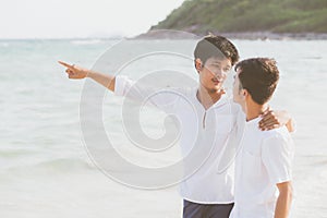 Homosexual portrait young asian couple standing pointing something together on beach in summer