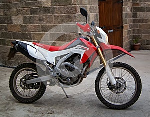 Honda CRF 250L parked by a stone building