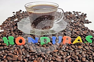 Honduras coffe beans on white surface with a cup of fresh brewed coffe name label 11