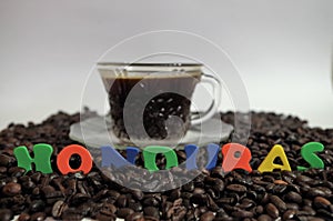 Honduras coffe beans on white surface with a cup of fresh brewed coffe name label 7