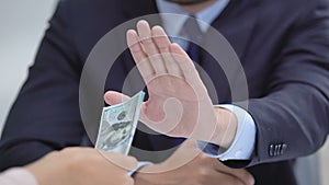 Honest businessman showing stop gesture, rejecting dollars offering, bribe