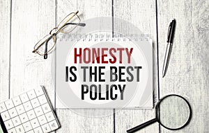honesty is the best policy words on notepad and pen, calculator and glasses