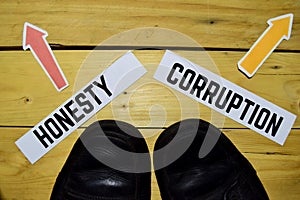 Honesty or Corruption opposite direction signs with sneakers on wooden