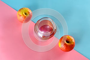 Honey and apples over blue pink background.