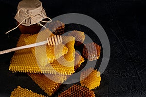 Honey background. Natural honey comb and a wooden spoon . On black rustic table