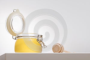 Honey background. Sweet honey in a glass jar and a honey spoon on a wooden table.