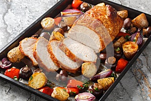 Honey baked pork loin with potatoes, onions, bell peppers and mushrooms close-up on a baking sheet. Horizontal