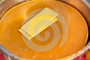 Honey beewax in bucket and plates of beeswax as close up