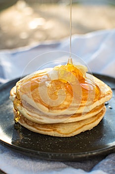 Honey being pour onto stack of pancake