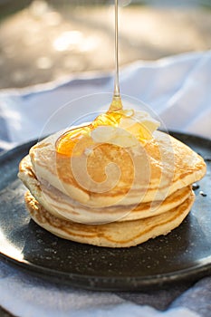 Honey being pour onto stack of pancake