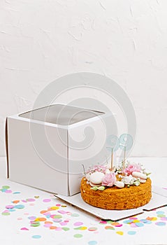 Honey cake with flowers and macarons on a box base next to windowed top