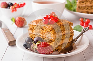 Honey cake with strawberries, mint and currant, a Cup of tea on a light background