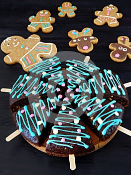 Honey cakes decorated as Christmas trees and gingerbread men and deers cookies in the background