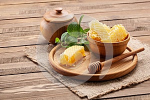 Honey comb in a wooden bowl on the background of wooden boards