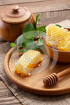 Honey comb in a wooden bowl on the background of wooden boards