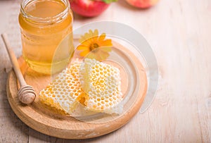 Honey dipper on the bee honeycomb background. Honey tidbit in glass jar and honeycombs wax