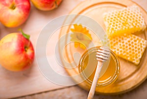 Honey dipper on the bee honeycomb background. Honey tidbit in glass jar and honeycombs wax