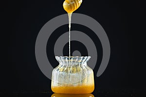 Honey dipper with flowing honey in glass jar