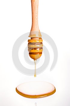 Honey drip from wooden dipper on white background