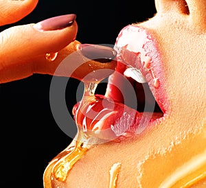 Honey dripping on girl lips. Beauty model woman eating honey