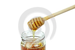 Honey dripping in glass jar and wooden dipper isolated on a white background, concept of bee products