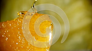 Honey dripping from honey dipper on honeycomb, over yellow background
