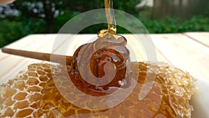 Honey dripping from honey dipper on honeycomb, over yellow background. 4k